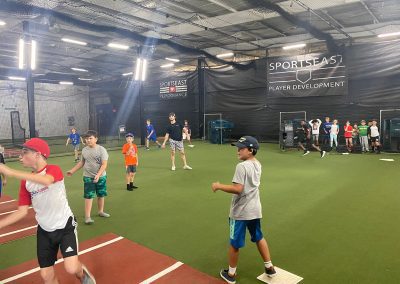 A group of young people playing baseball in an indoor facility.