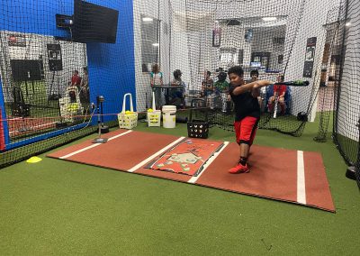 A man swinging a baseball bat at a batting cage.